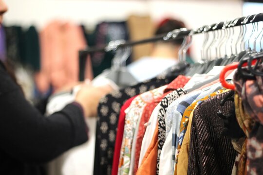 roupas em cabideiro em feira de segunda mao, consumo conciete de produtos texteis em economia circular.