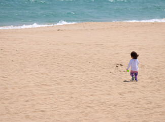 Small boy or girl running on the beach