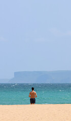 Man with his back turned, alone on the beach. Quiet vacation.