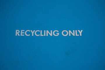 Close-up of the blue lid of a wheelie bin marked 