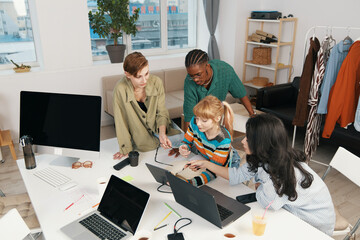 Young adult colleagues working together on a project in a bright workplace, socializing and...