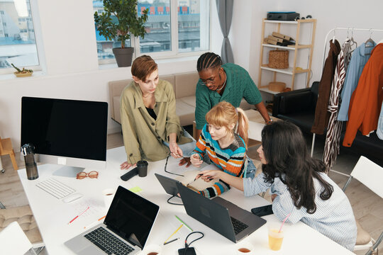 Young adult colleagues working together on a project in a bright workplace, socializing and collaborating effectively in a modern business environment with Gen Z coworkers.