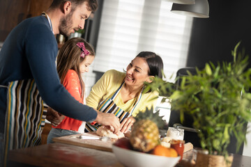 Parents in kitchen baking with their little girl learn through play most important life skills and values is in childhood.