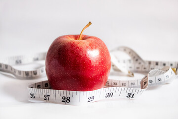 Red apple wrapped with measuring tape on a white background