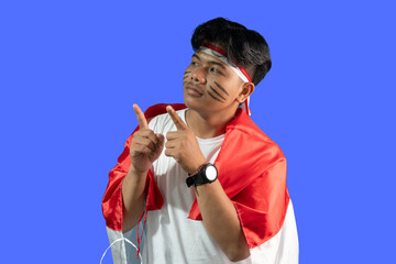 Proud Indonesian Man Celebrating National Pride, Pointing Upwards isolated on blue background