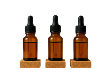 Three amber glass dropper bottles with black caps on cork stands