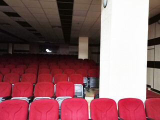 Dark empty cinema, theater stage with red curtains viewed from behind over rows of empty seats