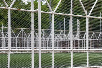 A clean white metal mesh fence enclosing a public outdoor sports court