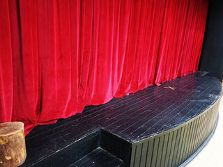 Dark empty cinema, theater stage with red curtains viewed from behind over rows of empty seats