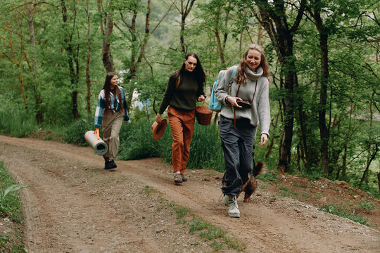 Middle age woman hiking with friends through forest path, active lifestyle, wellbeing and health focus - Powered by Adobe