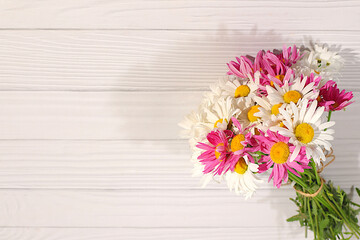 Bouquet of beautiful flowers of garden chamomile and mallow on wooden sunny background, advertising banner of spring and summer products, abstract floral arrangement, holiday card with place for text