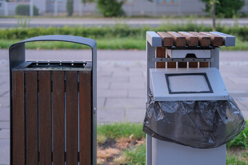 Two public waste bins placed side by side in an urban area, one made of metal and wood, the other...