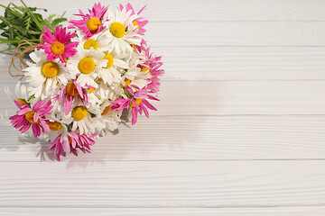 Bouquet of beautiful flowers of garden chamomile and mallow on wooden sunny background, advertising banner of spring and summer products, abstract floral arrangement, holiday card with place for text