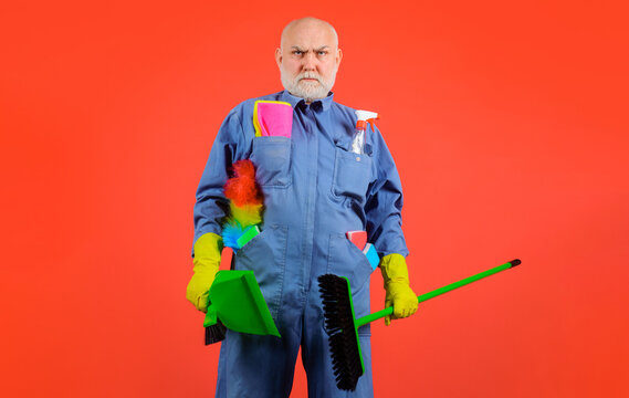 Professional cleaning service. Cleaner with sweeping tools and cleaning supplies. Cleaning agency. Serious bearded man in uniform with broom, dustpan and brush for carpet. Cleaning day. Housekeeping.