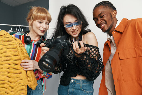 Young adult woman photographer with colleagues and friends socializing in vibrant workplace, showcasing Gen Z creativity and teamwork in modern business environment.