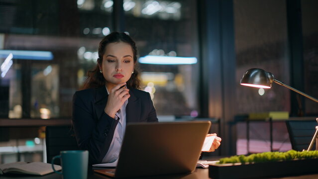 Lady manager doing paperwork at night office closeup. Woman reading documents