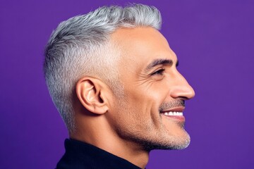 Fototapeta premium Purple solid background. A sophisticated gentleman in a well-lit studio. Chic men's two-block cut haircut - midlife middle eastern man with short hair. Visual idea of style for aging men.