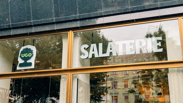 Prague, Czech Republic - June 23, 2025: UGO Salaterie storefront with modern design and large glass windows showcasing vibrant greenery and inviting atmosphere for healthy dining experience