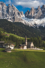 Santa Maddalena church and village in front of dramatic Geisler mountain peaks in the Dolomites, South Tyrol, Italy.