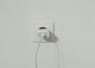 A white plug is plugged into a wall outlet
