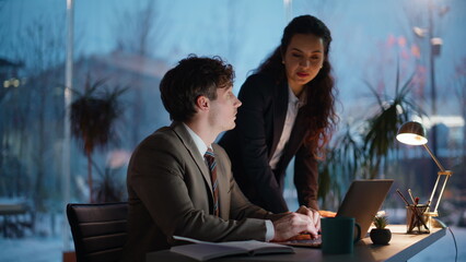 Friendly mentor helping intern in office work looking laptop. Woman talking man