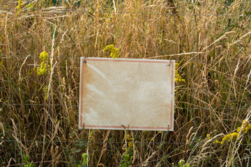 A sign is hanging in a field of tall grass