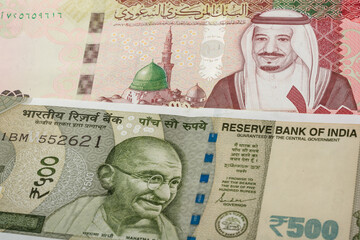100 Saudi riyal and 500 Indian Rupee banknotes. International trade concept