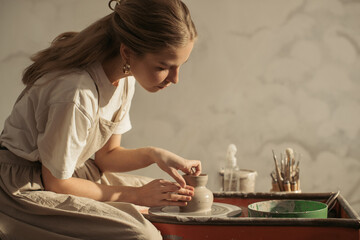 Young artisan creating pottery on a potter's wheel in workshop
