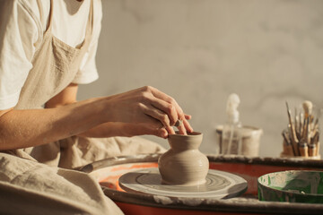 Potter creating small vase on pottery wheel in workshop