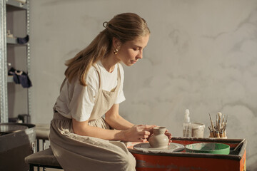 Ceramist creating clay jug on pottery wheel in workshop