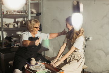 Senior and young potter showing thumbs up during pottery class