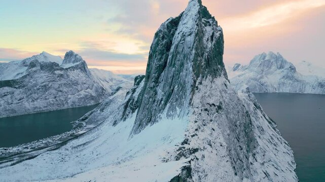 Segla auf der Insel Senja in Norwegen bei Sonnenuntergang im Winter, markante Felsformation vor klarem Himmel in kalter Lichtstimmung &uuml;ber schneebedeckter Fjord- und Berglandschaft