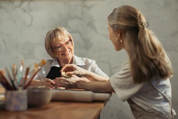 Senior woman learning pottery with teacher in workshop