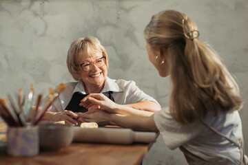 Senior woman enjoying pottery lesson with young instructor