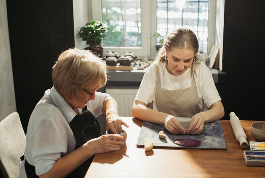 Senior and young women creating pottery in workshop
