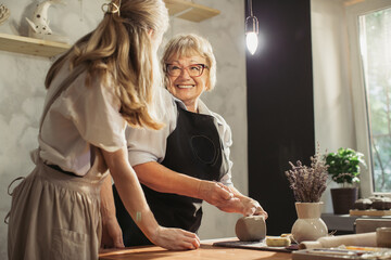 Senior woman learning pottery with teacher in workshop