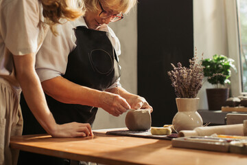Senior woman making pottery with clay in workshop
