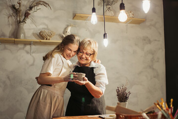 Senior woman and young apprentice admiring pottery in workshop