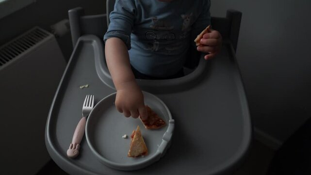 baby eating breakfast in high chair with toddler hand reaching food plate fork sandwich baby-led weaning toddler meal time natural light parenting lifestyle home interior child eating alone