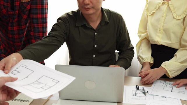Smart architect and safety engineer discussion about building plan on table with architectural document, measurement tools and wooden block scatter around at modern office. Closeup. Delineation.
