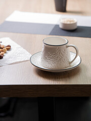 White beautiful handmade mug stands on light wooden table indoors