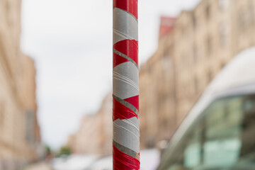 red and white striped warning tape wrapped around metal pole on urban street construction site with...