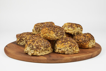 Whole grain concept. Homemade baked whole wheat rolls decorated with flaxseeds, close-up photo