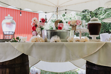 Outdoor wedding beverage station with galvanized ice tub, floral-accented LOVE letters and glass...
