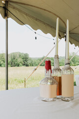 Upcycled glass bottles with dripping red and white wax holding taper candles on white tablecloth...