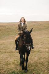 Woman Riding a Black Horse Through an Open Field With Natural Scenery