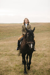 Woman Riding a Black Horse in a Picturesque Open Field
