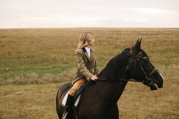 Young Woman Riding a Black Horse Across a Vast Open Field