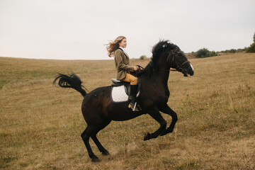 Young Woman Riding a Black Horse Across a Scenic Open Field