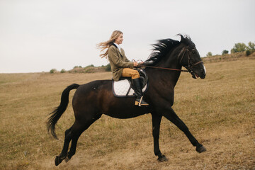 Young Equestrian Riding a Galloping Black Horse in Open Countryside